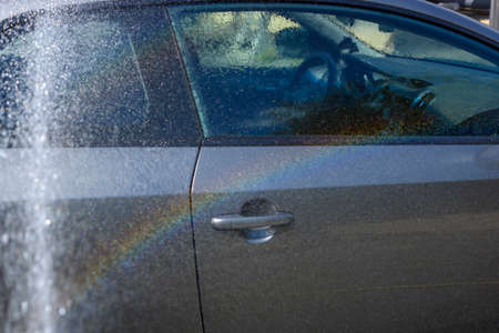 A water rainbow sparkled from splashing during a car wash