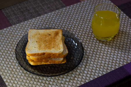 Ruddy toasts and glass of orange juice for breakfast on table