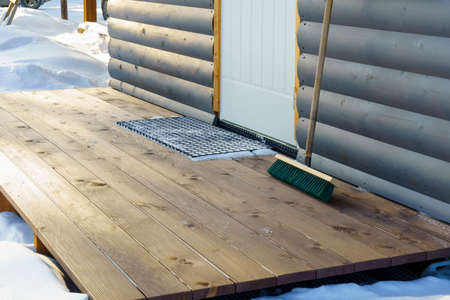 Plank porch of a wooden house in village is cleanly swept from snow in winterの写真素材