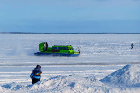 A hovercraft rushes across a lake covered with ice and snowのeditorial素材