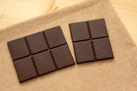 Chocolate bar on rustic sackcloth on a wooden tableの写真素材