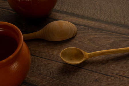 Kitchen utensils as clay pots and wooden spoons on wooden tableの写真素材