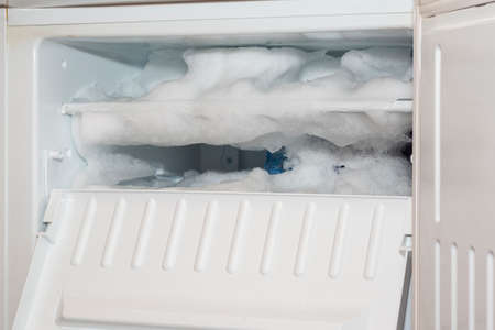 The fridge freezer is covered with a thick layer of ice and snowの写真素材
