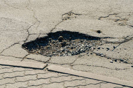 Dangerous pit in the asphalt surface of city roadの写真素材
