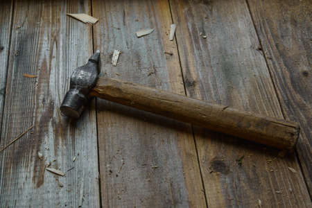 Vintage hammer on rough wooden workbench in light from windowの写真素材
