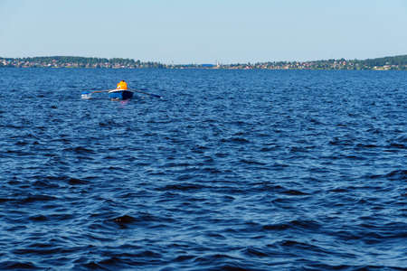Tourists in pleasure row boat and life jackets on lake bay in summer