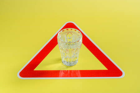 Alcohol shot of vodka in crystal glass in red triangle on yellow