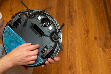Robot vacuum cleaner with wet rag and brushes in male hands in room to wet ragのeditorial素材
