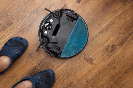 Robot vacuum cleaner upside down on floor in room with cloth and brushes upのeditorial素材