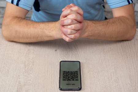 Man folded hands in prayer thanks God for QR code and vaccination against virusのeditorial素材