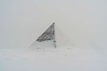 Pyramid at snowfall on frozen lake coast covered with snow on winterの写真素材