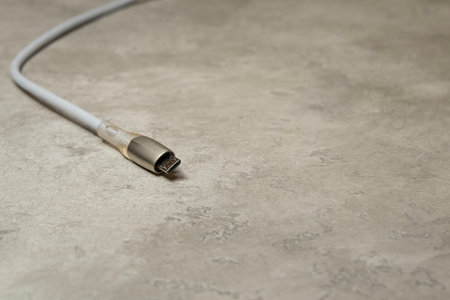 Micro USB charging cable on gray background. Charging cord for household electrical appliances