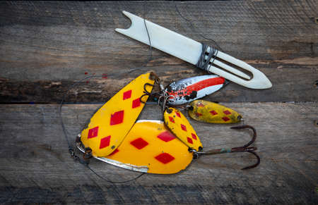 Closeup of fishing lures on a wooden board.