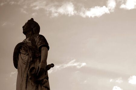 Aged Tombstone Statue against bright blue skyの写真素材