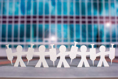 Human chain with vaccine in front of a glass facade - symbolic photo for the fight against the  pandemicの写真素材
