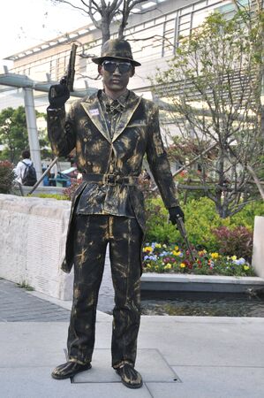 Human performance art: a handsome body painted camouflage roadside stand, pedestrians competing with photo.のeditorial素材