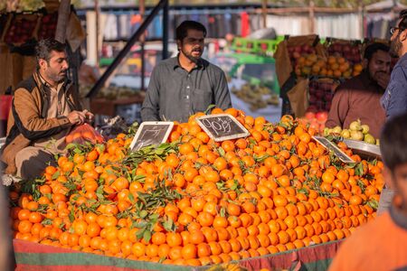 Islamabad, Islamabad Capital Territory, Pakistan - February 3, 2020, A seller is waiting for customers in the vegetable market to sell orange fruits.のeditorial素材