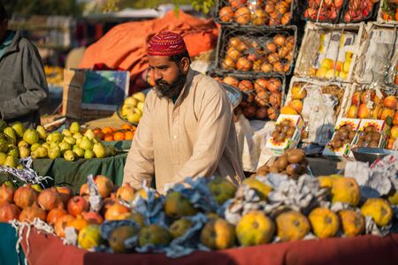 Islamabad, Islamabad Capital Territory, Pakistan - February 02, 2020, A seller is waiting for customers in the vegetable market to sell orange fruits.のeditorial素材