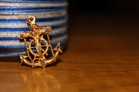 Anchor and rope on wooden table, closeup. Space for textの写真素材