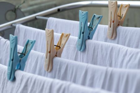 White clothes drying on standing clotheshores with clothespins white inner wear on Rack dryer Collapsible clothes horse with clothes plastic clothespinsの写真素材