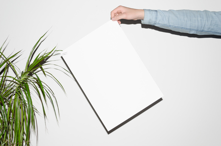 A3 Poster Mock-Up - Man in a denim shirt holding a poster on a white background. Hipster Aestheticの写真素材