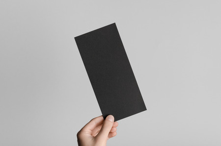 Black DL Flyer Mock-Up - Male hands holding a black flyer on a gray background.の写真素材