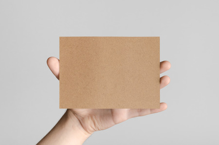 Kraft A6 Flyer / Postcard / Invitation Mock-Up - Male hands holding a kraft flyer on a gray background.の写真素材