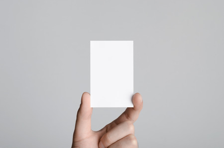 Business Card Mock-Up (85x55mm) - Male hands holding a blank card on a gray background.の写真素材