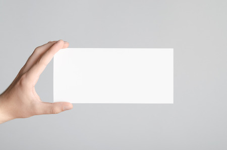 DL Flyer Mock-Up - Male hands holding a blank flyer on a gray background.の写真素材