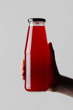 Juice Bottle Mock-Up - Male hands holding a juice bottle on a gray backgroundの写真素材