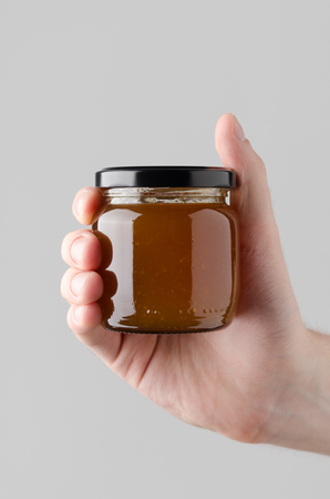 Apricot Jam Jar Mock-Up - Male hands holding a jam jar on a gray backgroundの写真素材