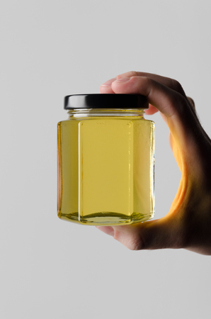 Honey Jar Mock-Up - Male hands holding a honey jar on a gray backgroundの写真素材