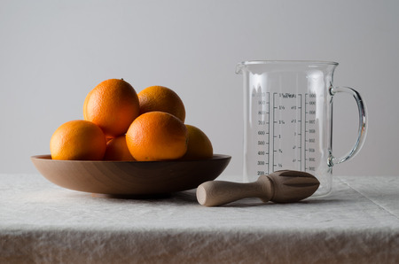 Oranges in a wooden bowl on a white linen tablecloth.の写真素材