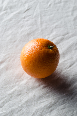 Orange on a white linen tablecloth.の写真素材