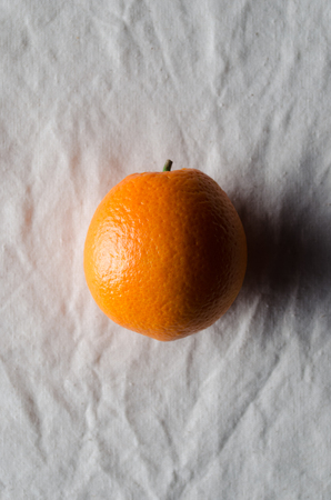 Orange on a white linen tablecloth.の写真素材