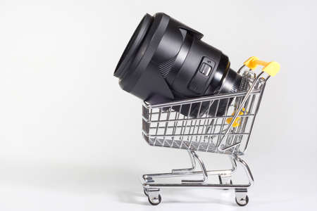 A lens in a shopping cart. Buying photo technics