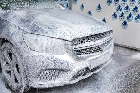 Washing car with soap. Car washing concept. Car in foam.の写真素材