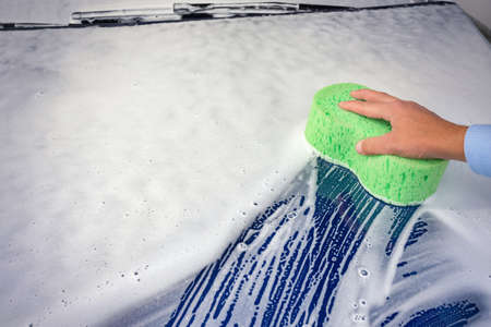 C man cleaning automobile with sponge at car wash. Ar wash with soap.の写真素材