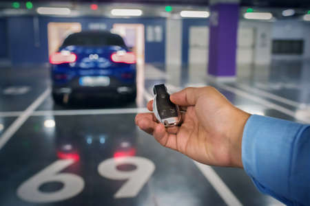 Car keys in a hand of the person against the background of the car. underground parking.の写真素材