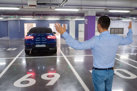 Happy man on a background a new car, in the underground parking.の写真素材