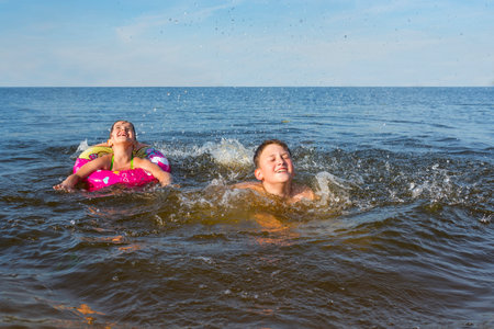 A happy brother and sister, swimming in the open sea on a bright sunny day.の写真素材