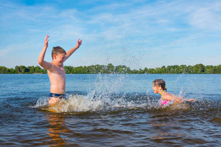 Children in the river are splashed with water. A hot sunny summer day.の写真素材