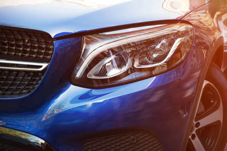 Beautiful headlight of blue car by close-up in a sunny day. Kind with to the side.の写真素材