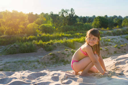 Little girl plays with sand on a summer beach on a sunny day. Active summer gamesの写真素材