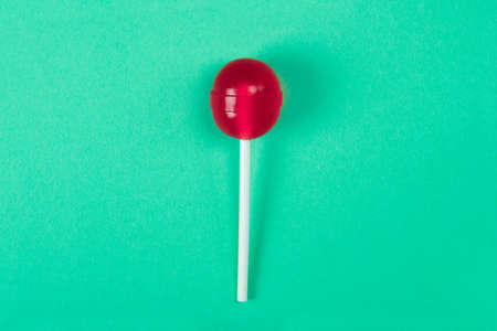 A red lollipop on a stick at the green background, a view from above, sweets and caramel.の写真素材