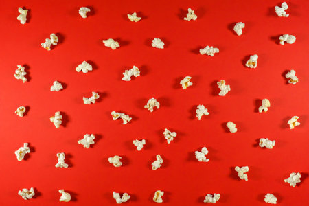 Texture of salted popcorn on a red background. Top view of popcorn texture background.