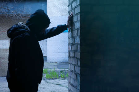 Silhouette of a man standing against a wall. The fight against crime and drug addiction. Social problems.の写真素材