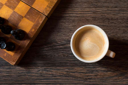 Cup of coffee and chess-board on a wooden background. Kind from above.の写真素材