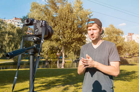 A blogger in the park records a video blog on camera. Online communication, consultations, training, business. Distance lifestyle conceptの写真素材