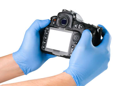 Male hands in blue medical gloves are holding a camera isolated on white. Gloves for protection...
